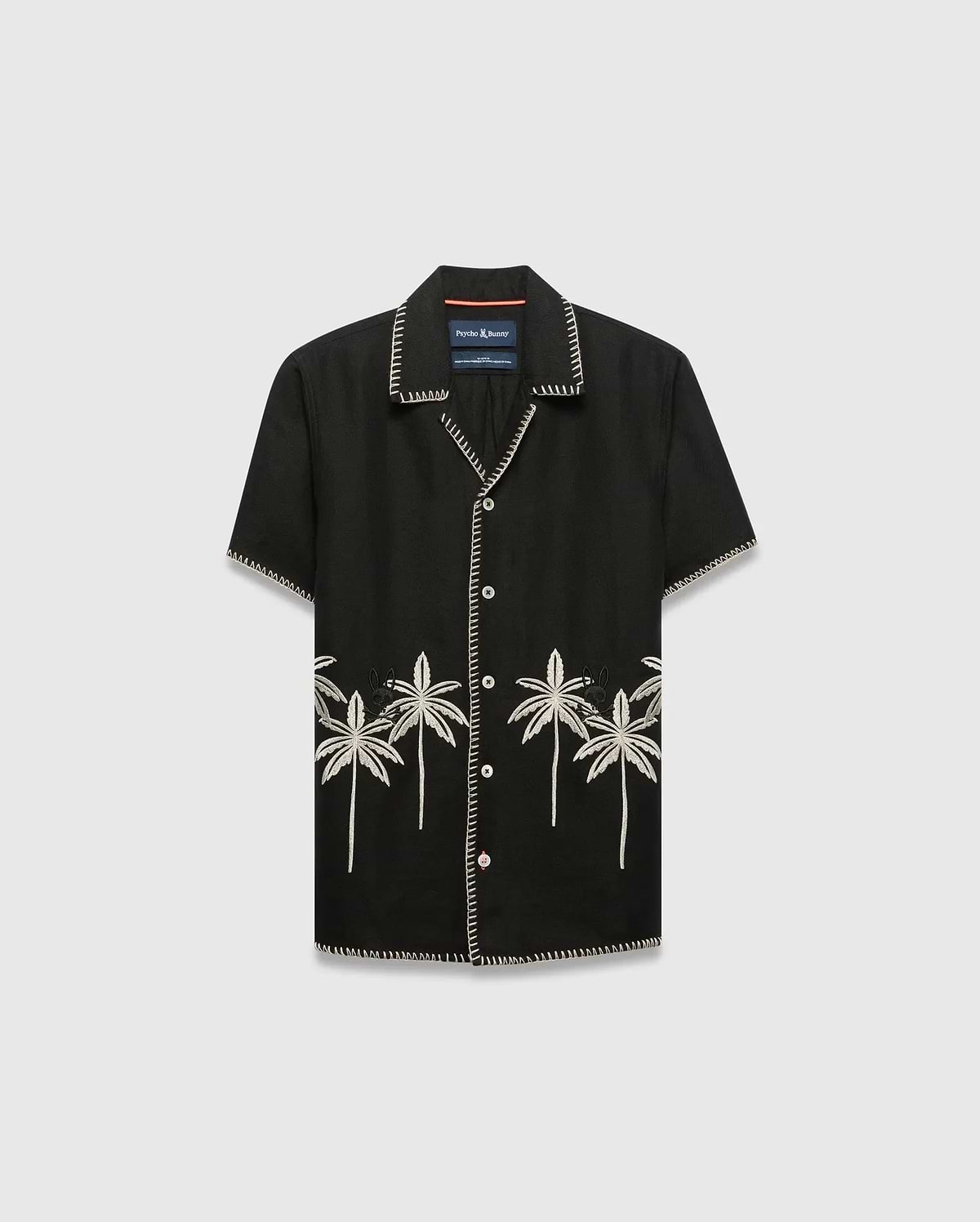 Kids Brad Linen Shirt, black relaxed fit with white contrast stitching, white buttons, and cream embroidered palm trees featuring a small Psycho Bunny skull logo on the lower front.