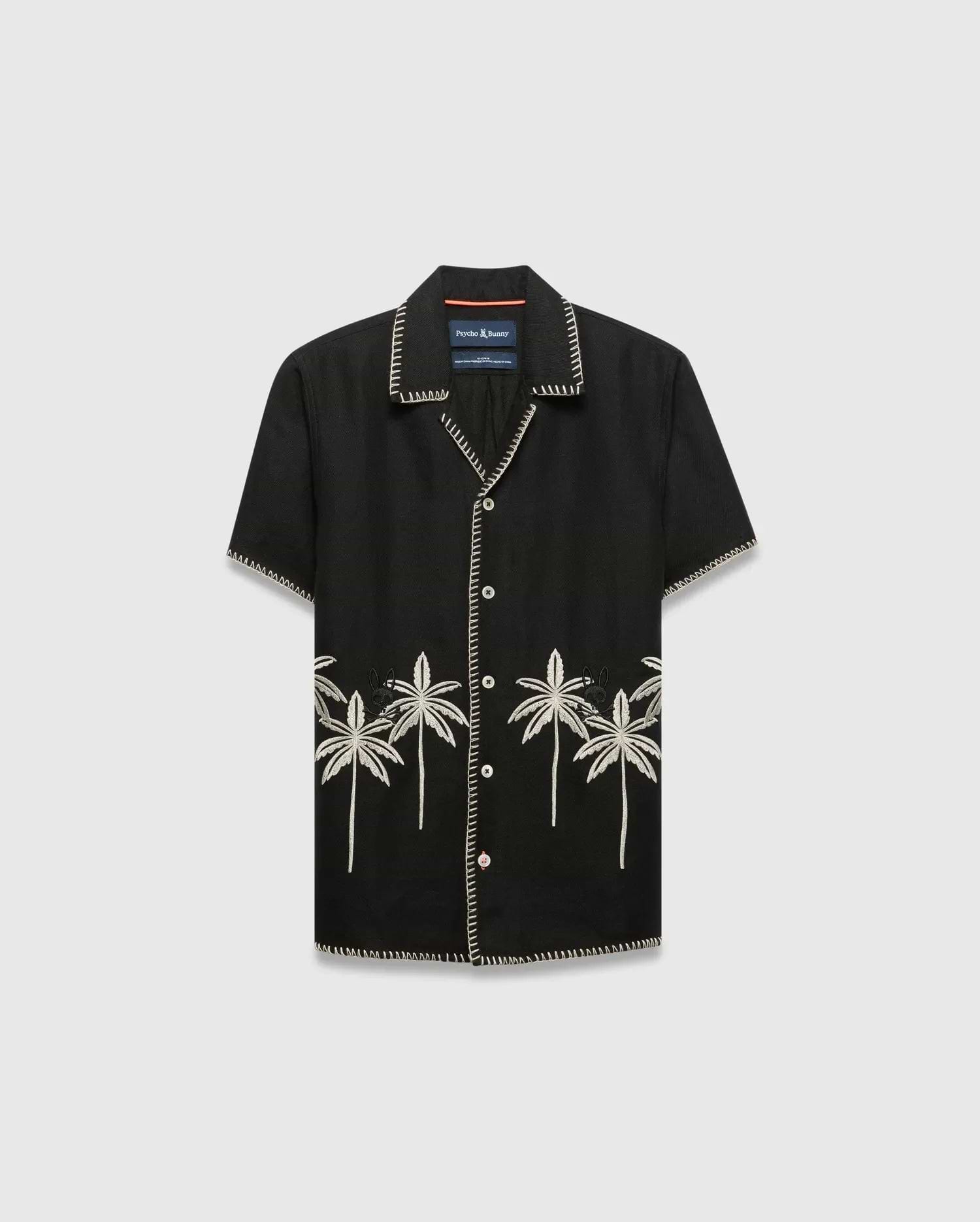 Kids Brad Linen Shirt, black relaxed fit with white contrast stitching, white buttons, and cream embroidered palm trees featuring a small Psycho Bunny skull logo on the lower front.
