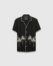Kids Brad Linen Shirt, black relaxed fit with white contrast stitching, white buttons, and cream embroidered palm trees featuring a small Psycho Bunny skull logo on the lower front.