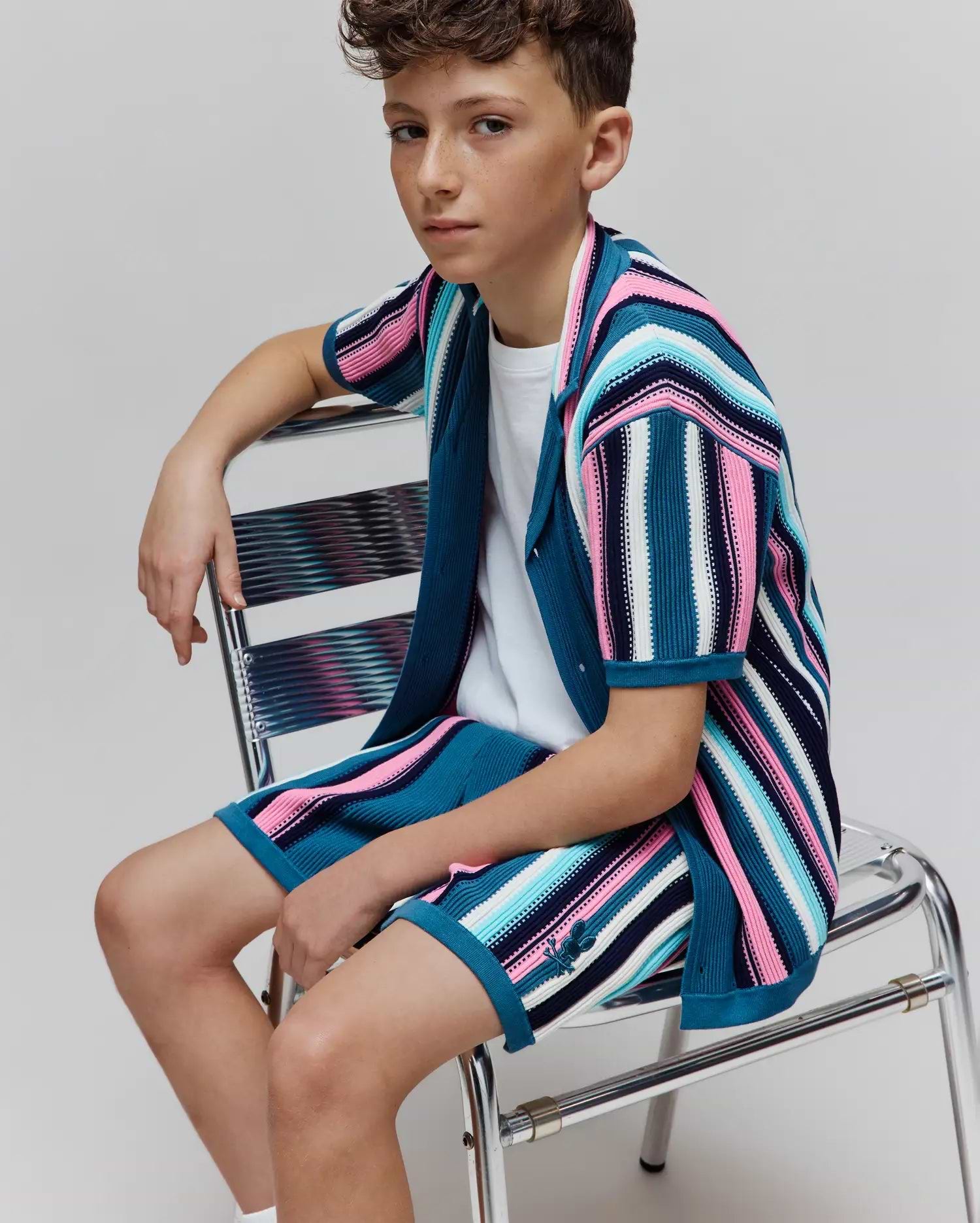 KIDS CLIFF KNIT SHIRT and matching shorts, a relaxed knit set with vibrant multi-color stripes in teal, pink, blue, navy, and white, featuring a small embroidered Psycho Bunny skull logo on the shorts. (2)