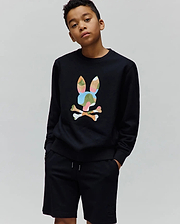 Black Kids Ara Crew sweatshirt, relaxed fit, featuring a large, vibrant multi-color camouflage Psycho Bunny skull logo on the chest, paired with black jersey shorts with a small tonal embroidered bunny skull logo.