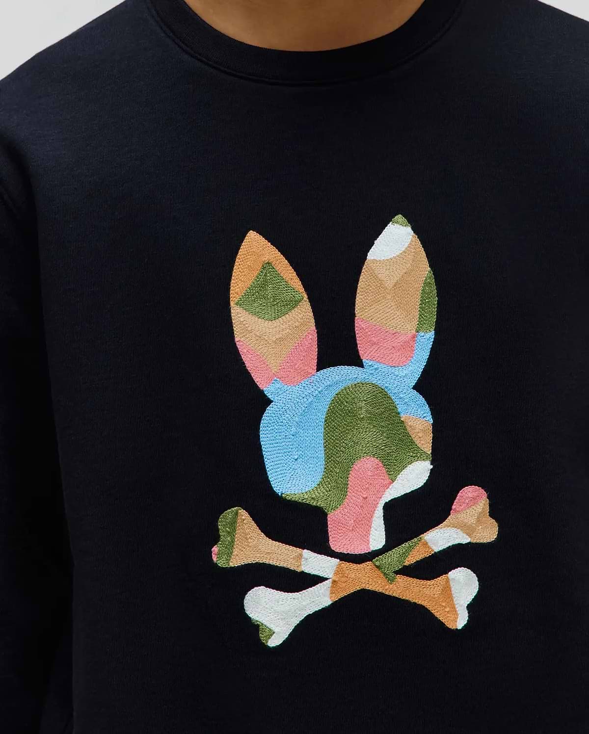 Black Kids Ara Crew sweatshirt featuring a large, central embroidered Psycho Bunny skull logo in a vibrant patchwork of blue, green, pink, orange, and white on smooth jersey fabric.