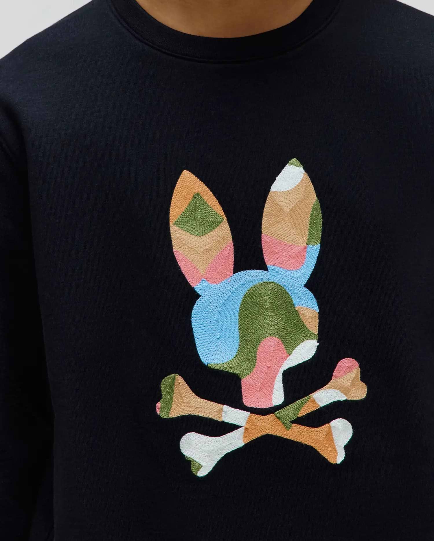 Black Kids Ara Crew sweatshirt featuring a large, central embroidered Psycho Bunny skull logo in a vibrant patchwork of blue, green, pink, orange, and white on smooth jersey fabric.