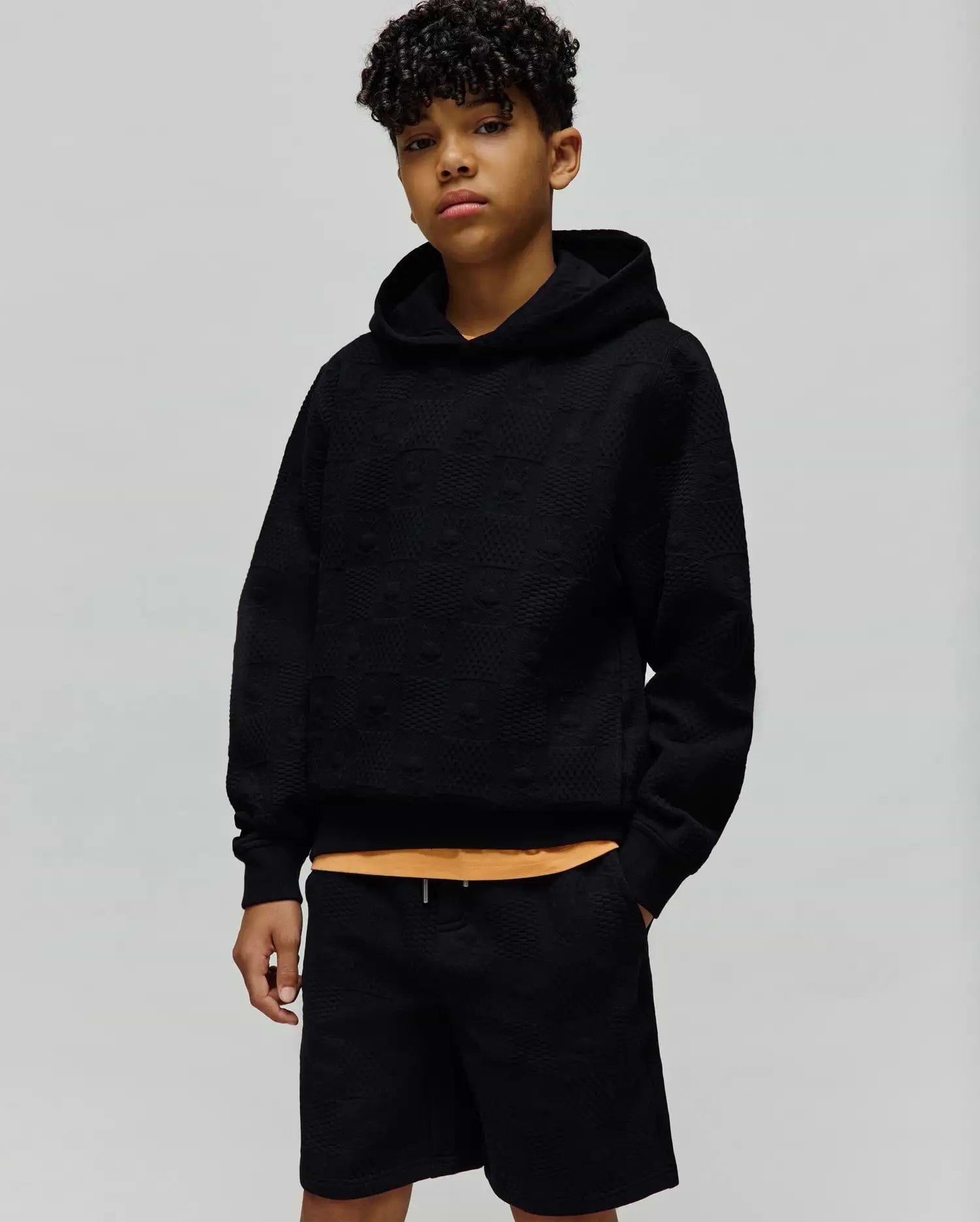 Kids Dustin Hoodie, a black relaxed fit hoodie featuring an all-over embossed Psycho Bunny skull pattern on textured knit fabric, with a subtle orange accent. (4)