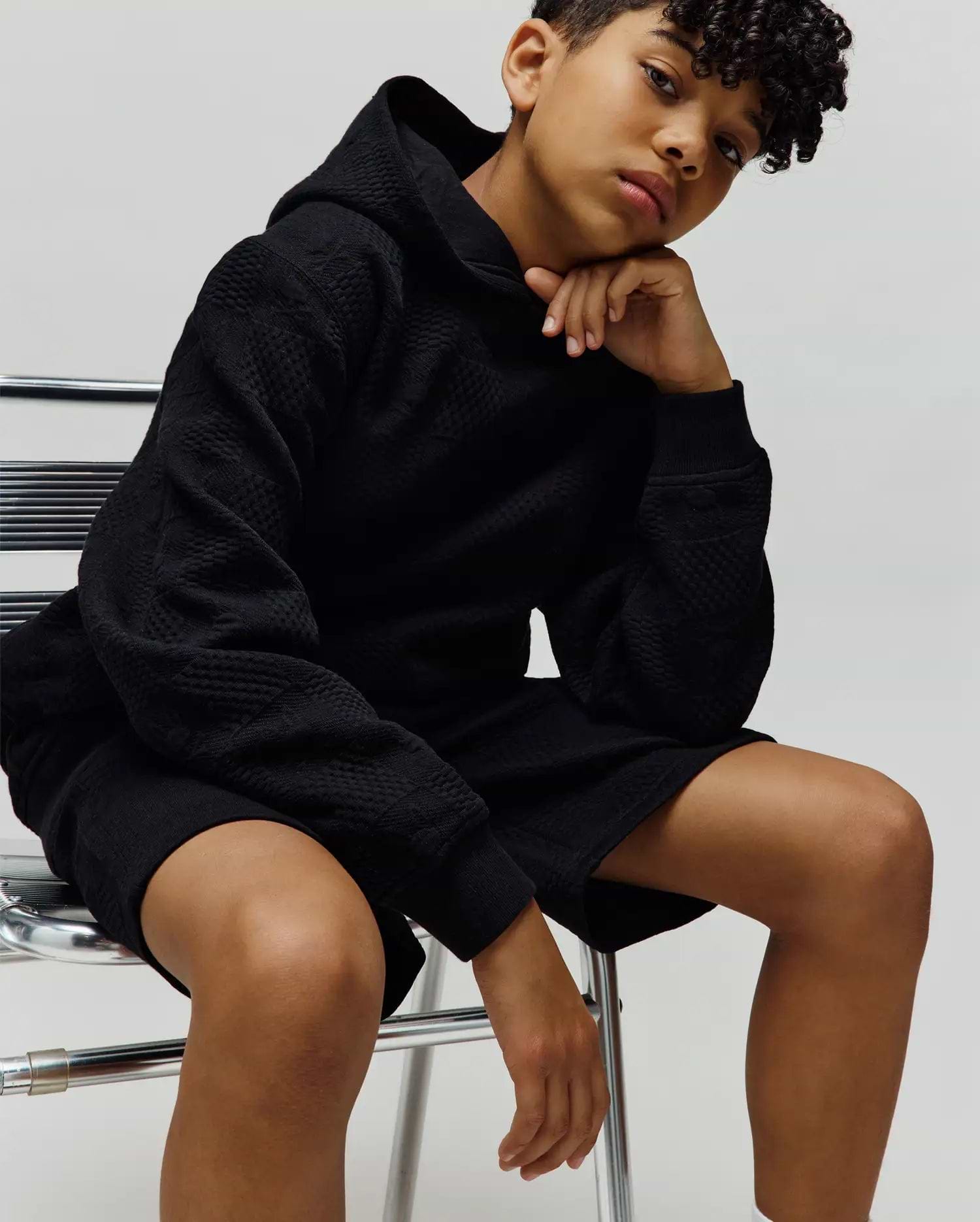 Psycho Bunny Kids Dustin Hoodie in black, featuring a relaxed fit and an all-over raised, textured geometric pattern. Paired with matching black textured shorts. (1)
