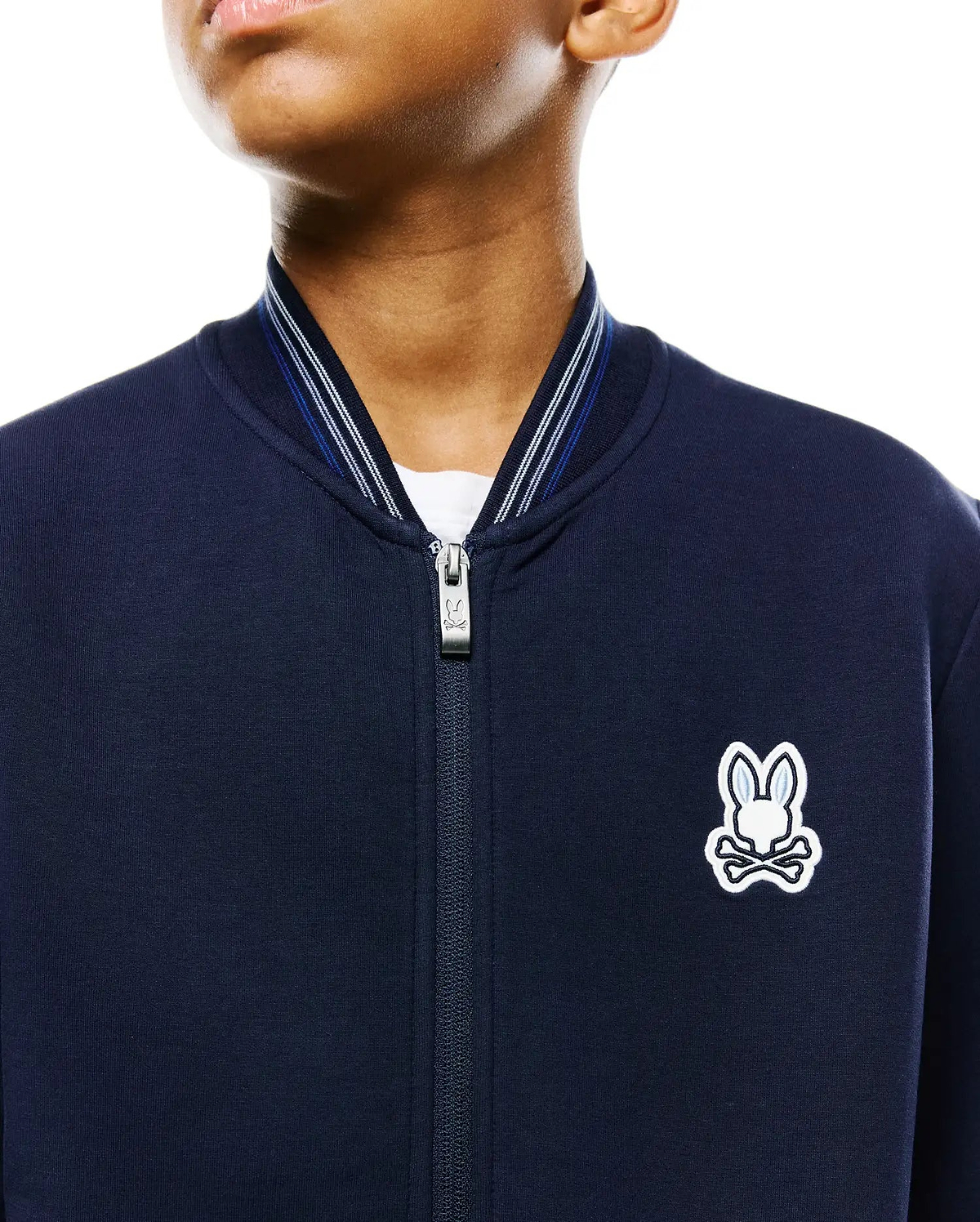 Kids Jaydon Track Jacket, navy smooth jersey, classic fit, full-zip with branded pull, ribbed collar with white and blue stripes, and an embroidered white and light blue Psycho Bunny skull logo on the left chest.