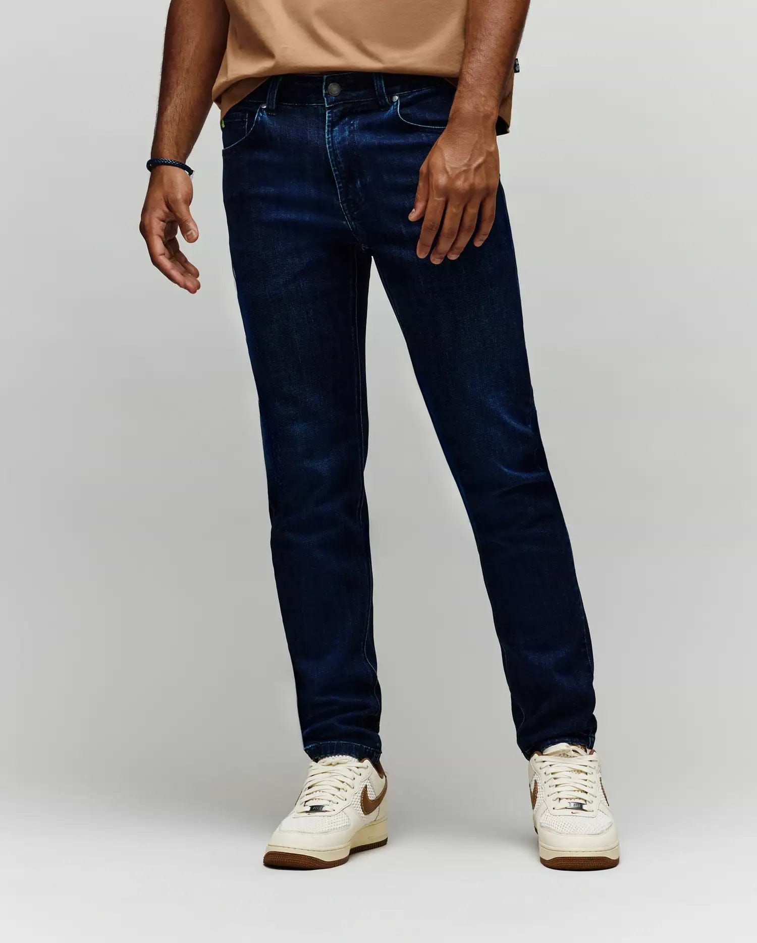 Mens Emerson Denim Pant, dark indigo slim fit denim jeans with classic five-pocket styling, subtle whiskering, and a small green Psycho Bunny logo tag on the coin pocket.