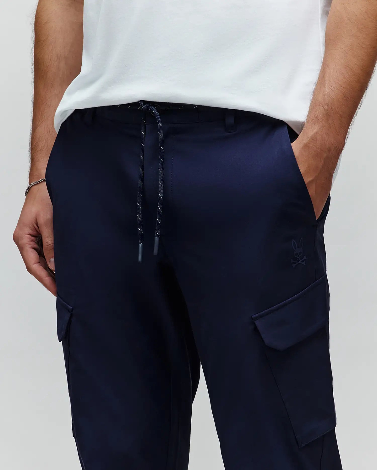 Mens Luka Cargo Pant in navy, featuring a relaxed fit, smooth fabric, drawstring waist with flecked cord, and a small tonal embroidered Psycho Bunny skull logo above the right cargo pocket. (2)