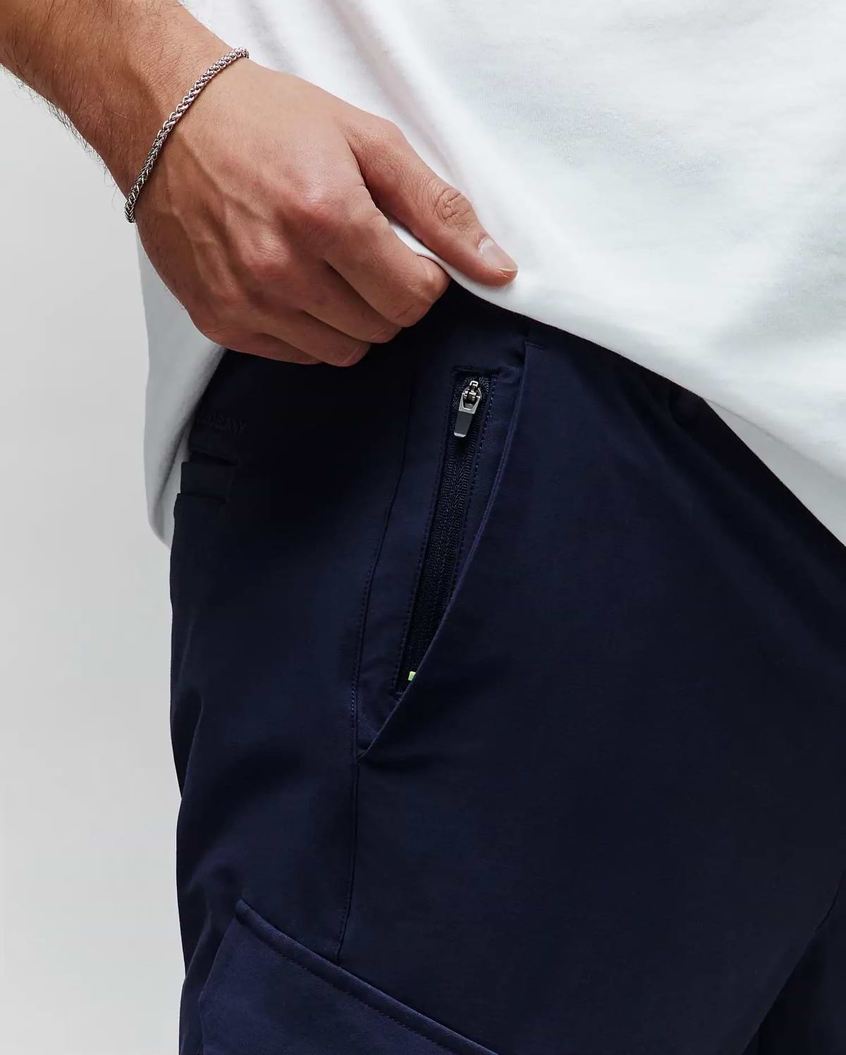Mens Luka Cargo Pant in navy, featuring a zippered side pocket with a neon green accent, subtle Psycho Bunny branding on the waistband, and a smooth fabric texture. (4)