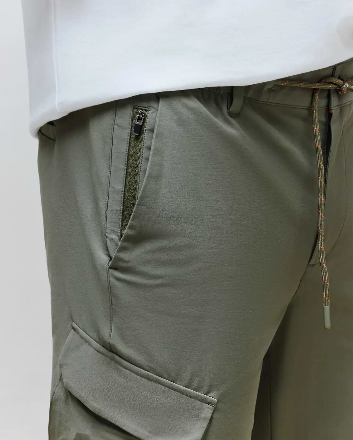 Mens Luka Cargo Pant in olive green, featuring a relaxed fit, smooth fabric, a zippered thigh pocket, and a cargo flap pocket, with an orange-flecked drawstring waist. (4)