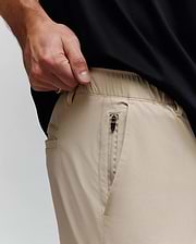 Mens Luka Cargo Pant in khaki, a relaxed fit with smooth fabric, elastic waistband, zippered side pocket with black pull, and subtle Psycho Bunny text logo on the side.