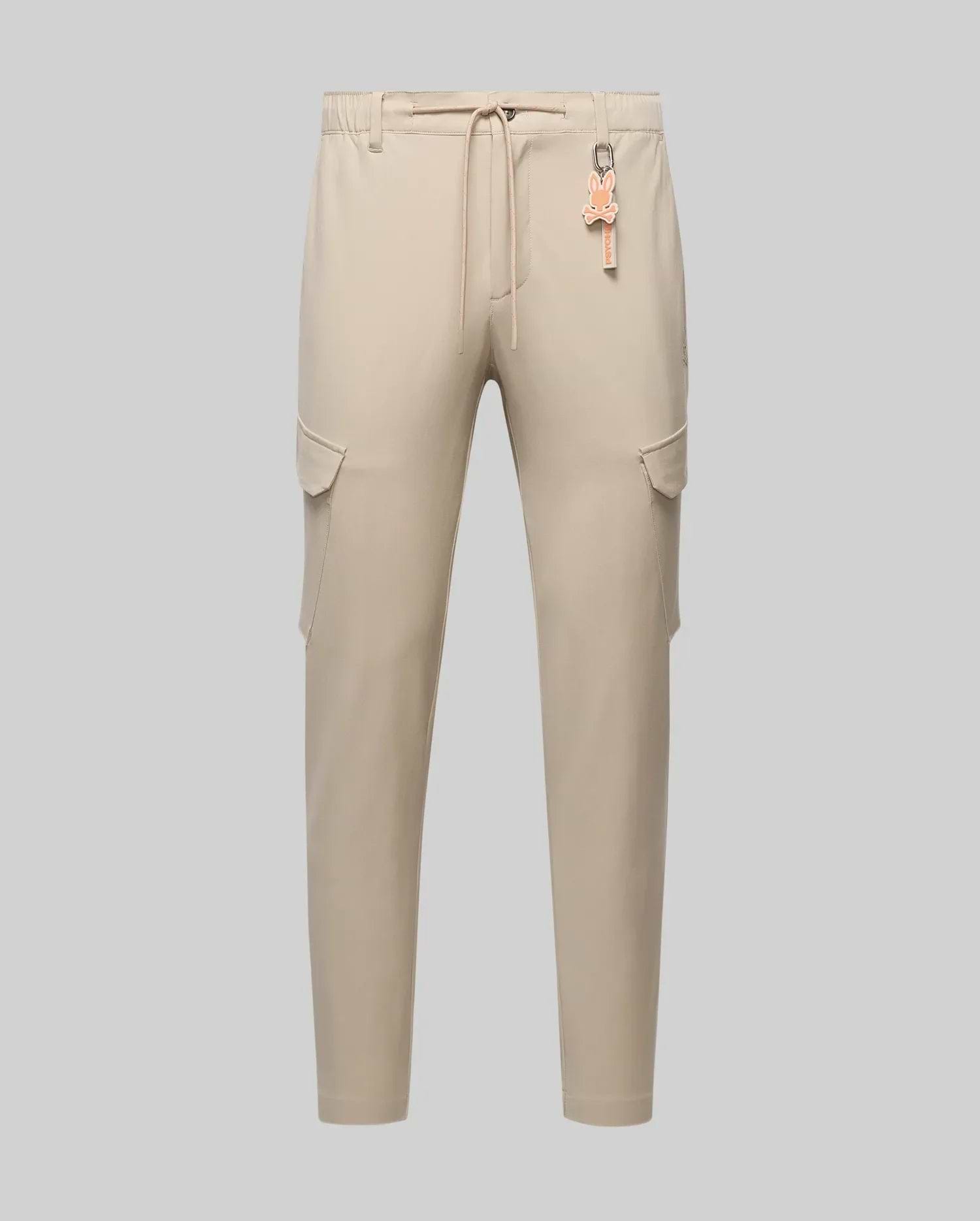 Mens Luka Cargo Pant in beige, featuring a relaxed fit, smooth fabric, side cargo pockets, and an elastic drawstring waist with an attached orange Psycho Bunny skull logo keychain.