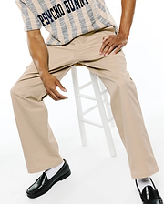 MENS AIDAN CHINO PANT in relaxed fit khaki twill, paired with a cream and navy striped textured knit short-sleeve shirt featuring large PSYCHO BUNNY text across the chest.