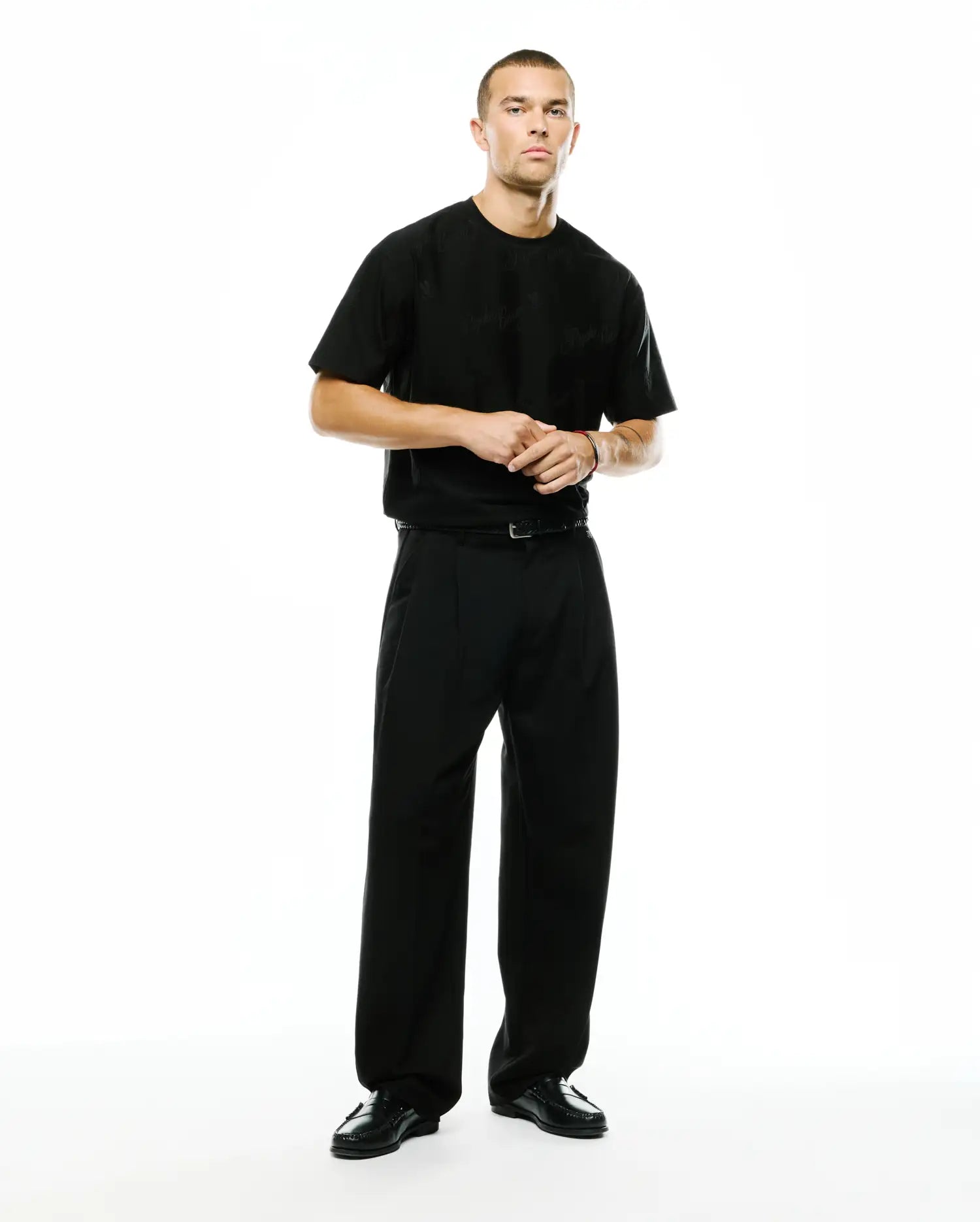 Black relaxed-fit jersey t-shirt featuring a subtle tonal Psycho Bunny skull logo on the left chest, paired with Men's Wayde Wide-Leg Pleated Pants in a smooth black fabric. (1)