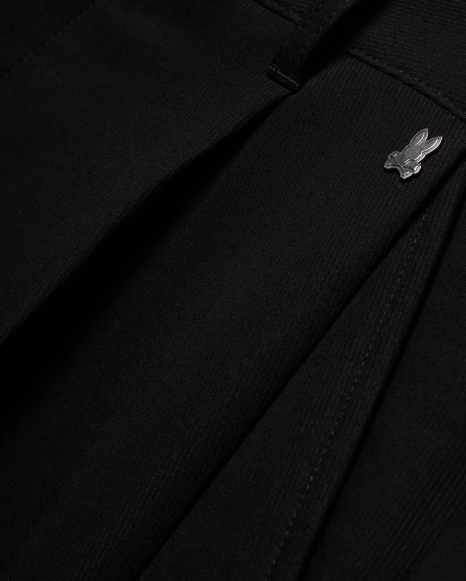 Men's Wayde Wide-Leg Pleated Pants in black, featuring a subtle fabric texture, wide-leg fit, and a small metallic silver Psycho Bunny skull logo near the waistband. (6)