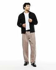 Men's Wayde Wide-Leg Pleated Pants in beige, featuring a relaxed fit and smooth fabric, styled with a black overshirt with chest pockets and a white t-shirt. No visible Psycho Bunny logo. (1)