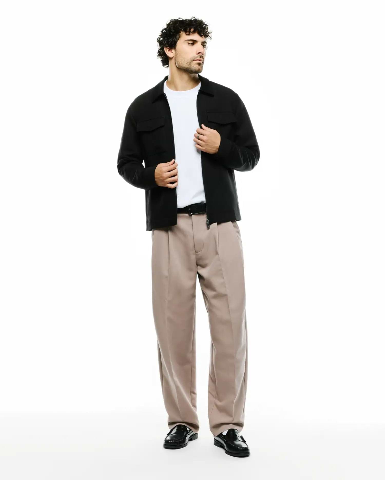 Men's Wayde Wide-Leg Pleated Pants in beige, featuring a relaxed fit and smooth fabric, styled with a black overshirt with chest pockets and a white t-shirt. No visible Psycho Bunny logo. (1)