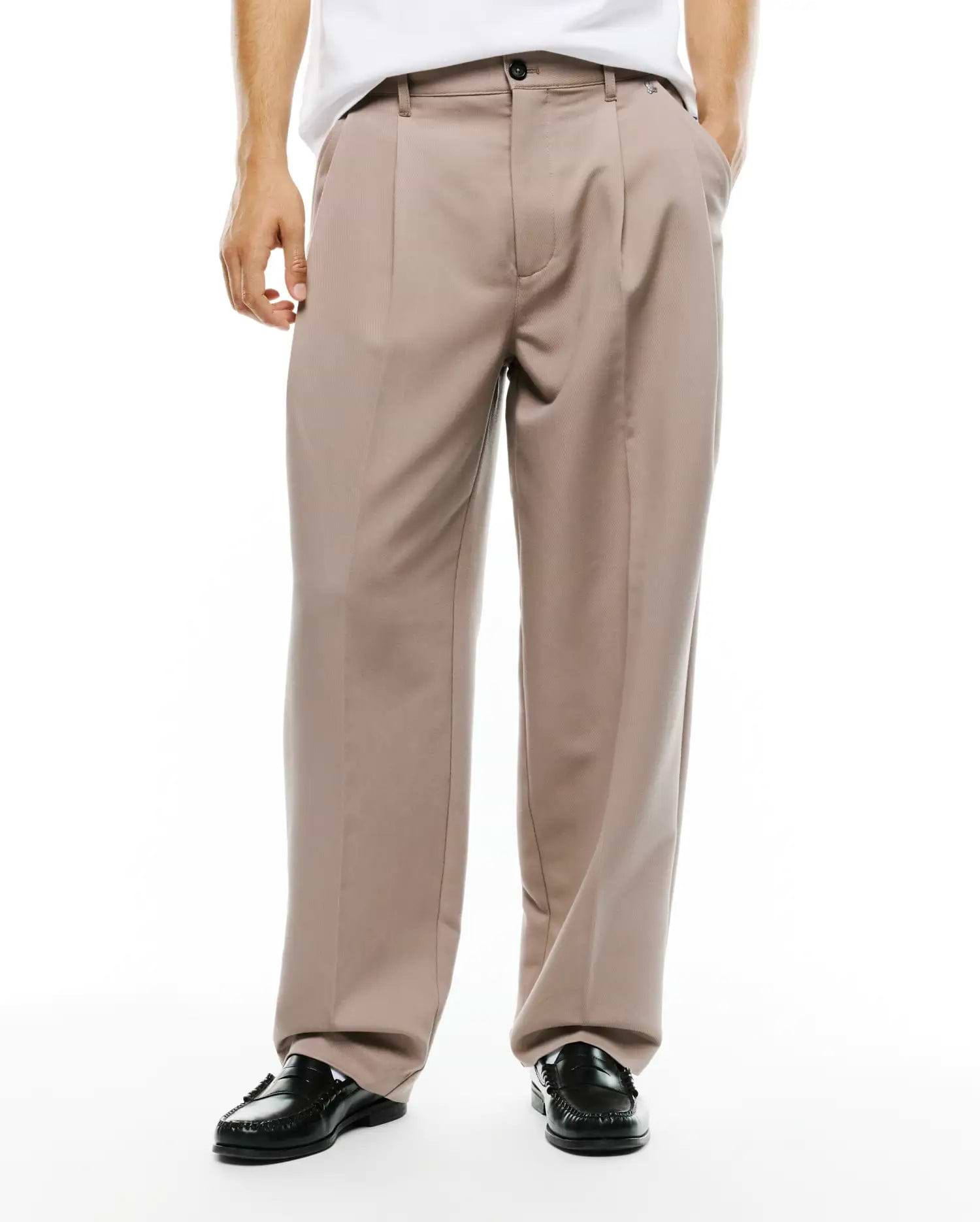 Men's Wayde Wide-Leg Pleated Pants in taupe, featuring a relaxed wide-leg fit, smooth woven fabric, front pleats, a black button closure, and a small embroidered Psycho Bunny skull logo near the right front pocket. (2)