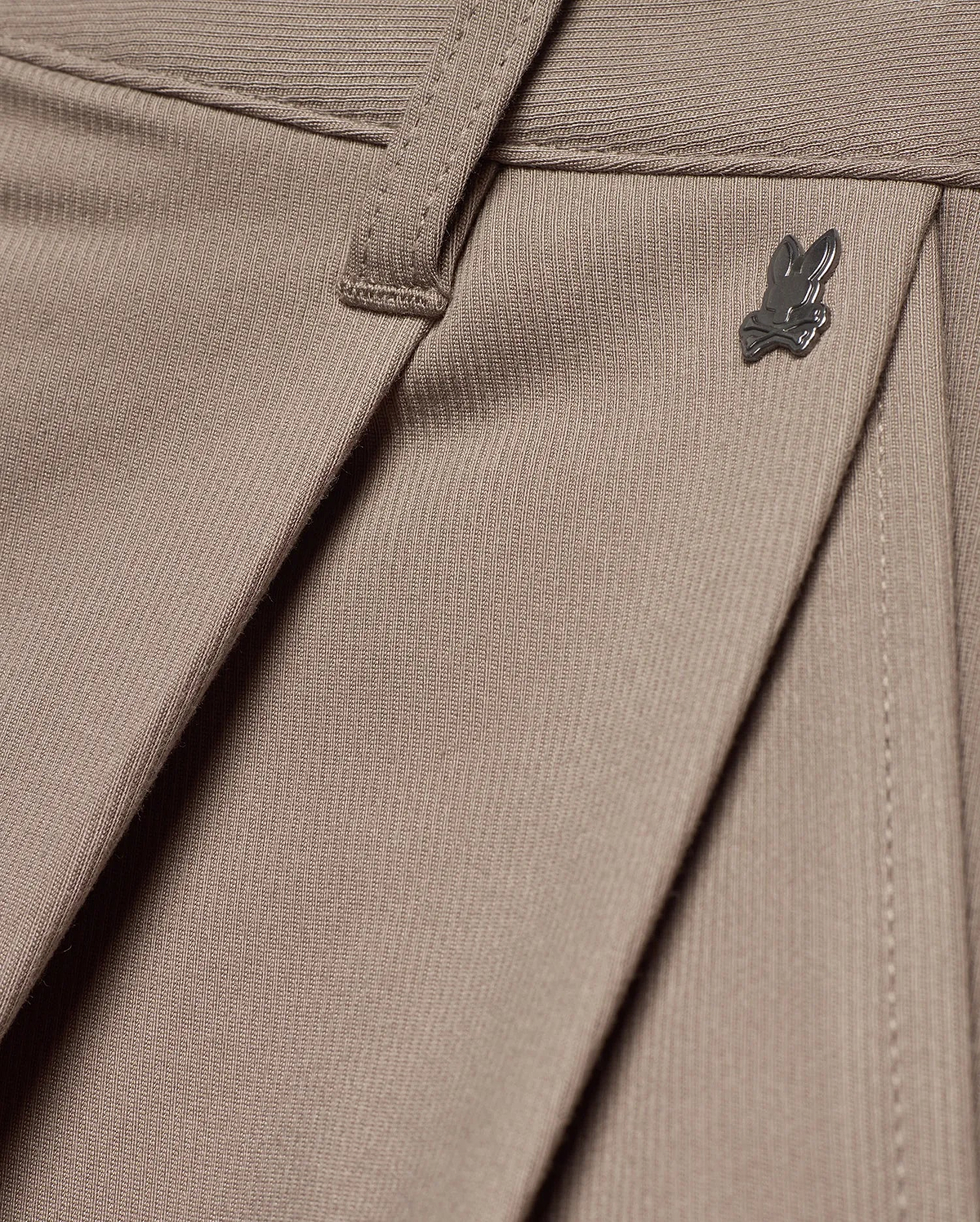 MEN'S WAYDE WIDE-LEG PLEATED PANTS in taupe, featuring a subtle ribbed knit texture, front pleats, and a small dark metal Psycho Bunny skull logo near the waistband. (6)