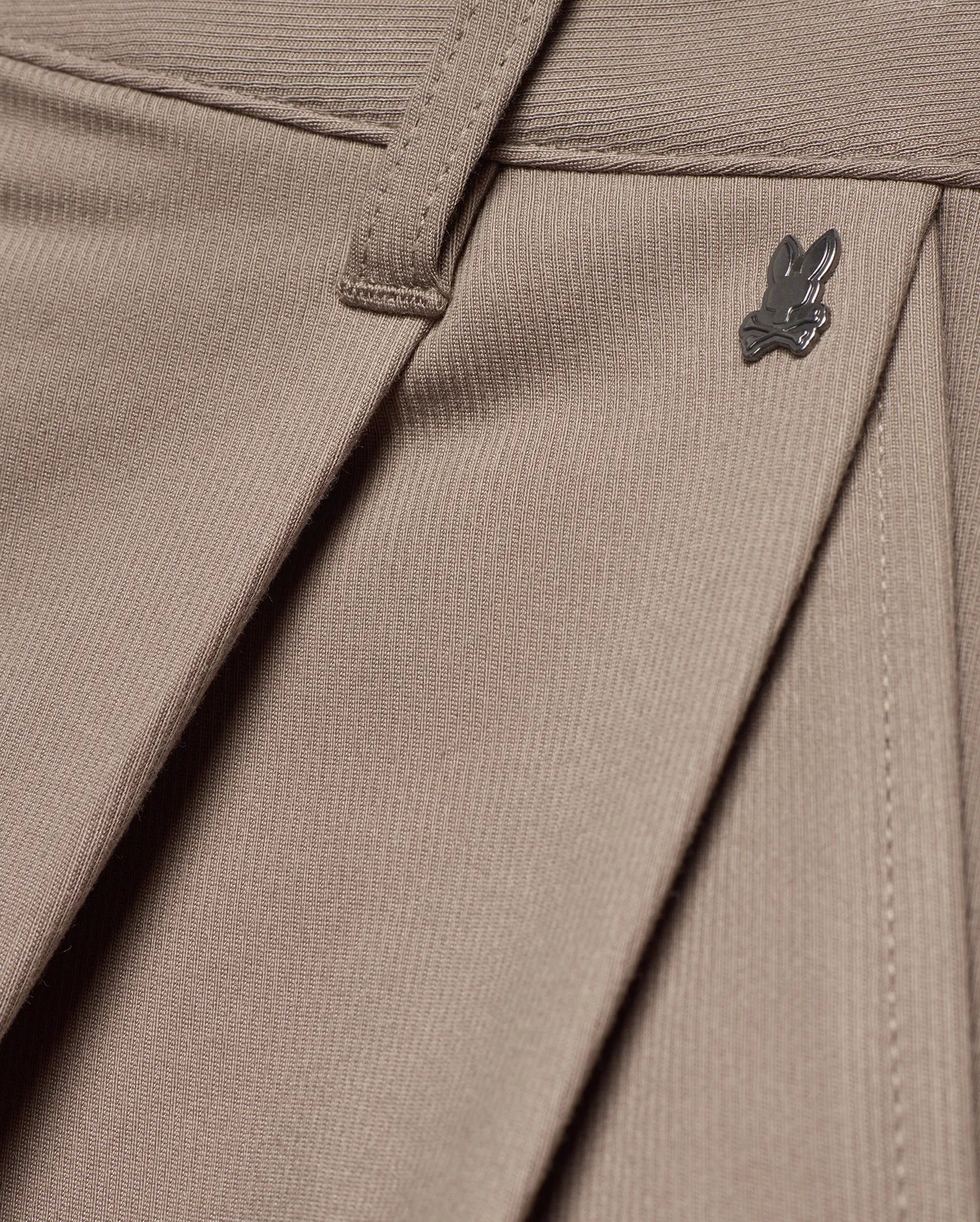 MEN'S WAYDE WIDE-LEG PLEATED PANTS in taupe, featuring a subtle ribbed knit texture, front pleats, and a small dark metal Psycho Bunny skull logo near the waistband. (6)