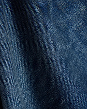Mens Beck Denim Relaxed Pant in a rich, medium blue wash, showcasing a durable twill weave with subtle white thread accents and natural folds, creating a comfortable, lived-in texture.
