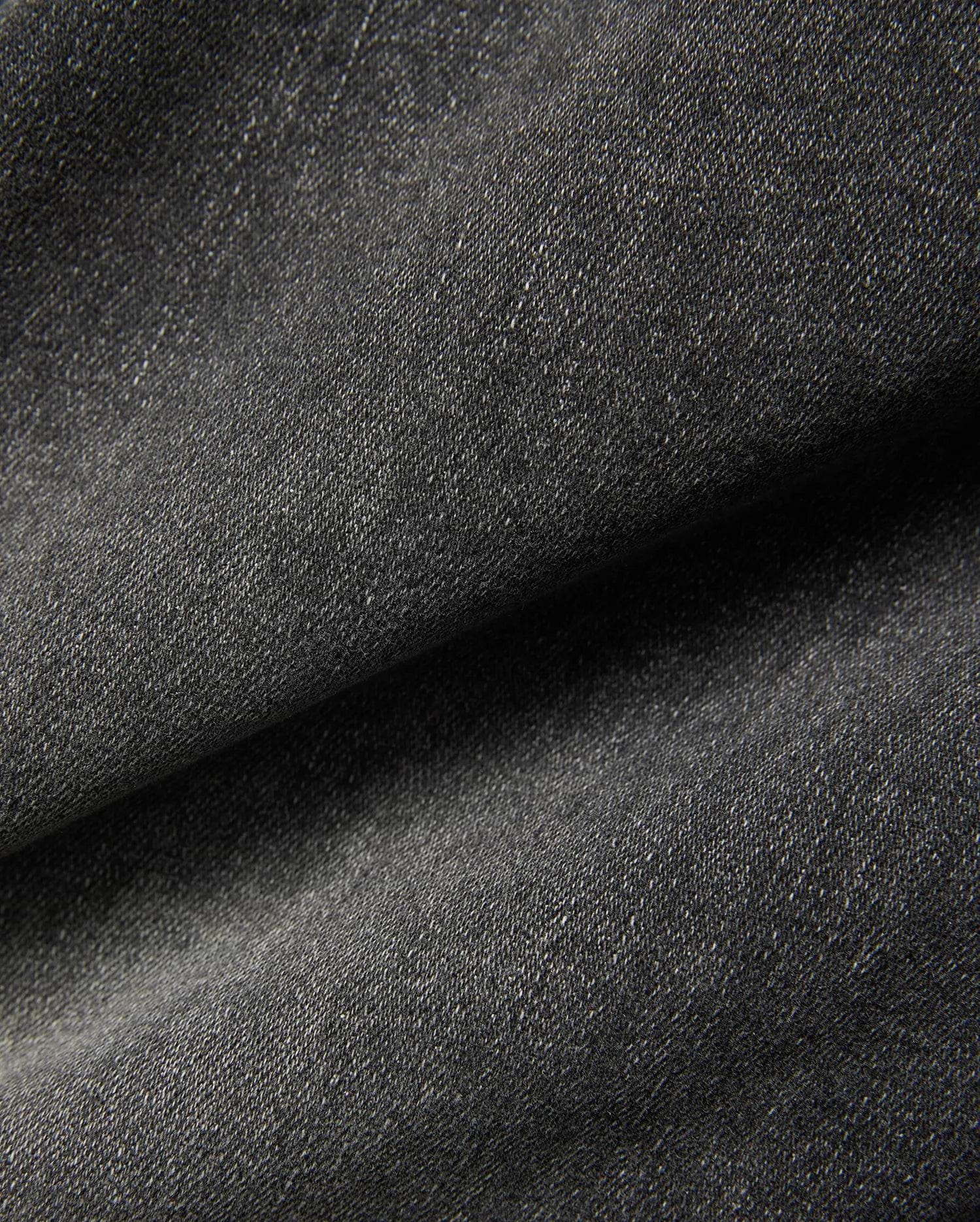 Mens Emerson Denim Pant featuring a dark charcoal grey denim fabric with a visible twill weave and subtle light flecks, creating a textured, washed appearance. (6)