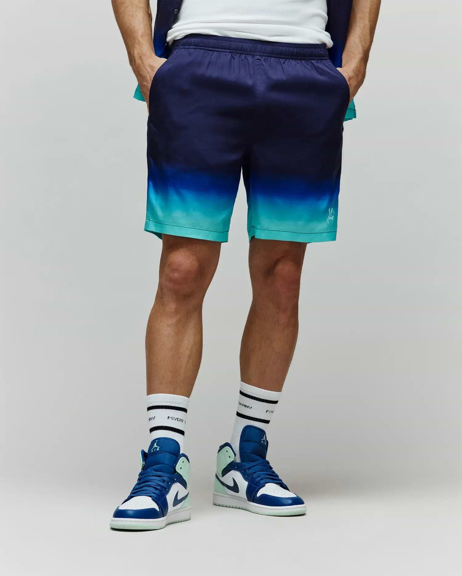 Mens Dax Tencel Short, relaxed fit, featuring a smooth fabric with a dark navy to bright teal gradient, and a small white Psycho Bunny skull logo on the lower right leg.