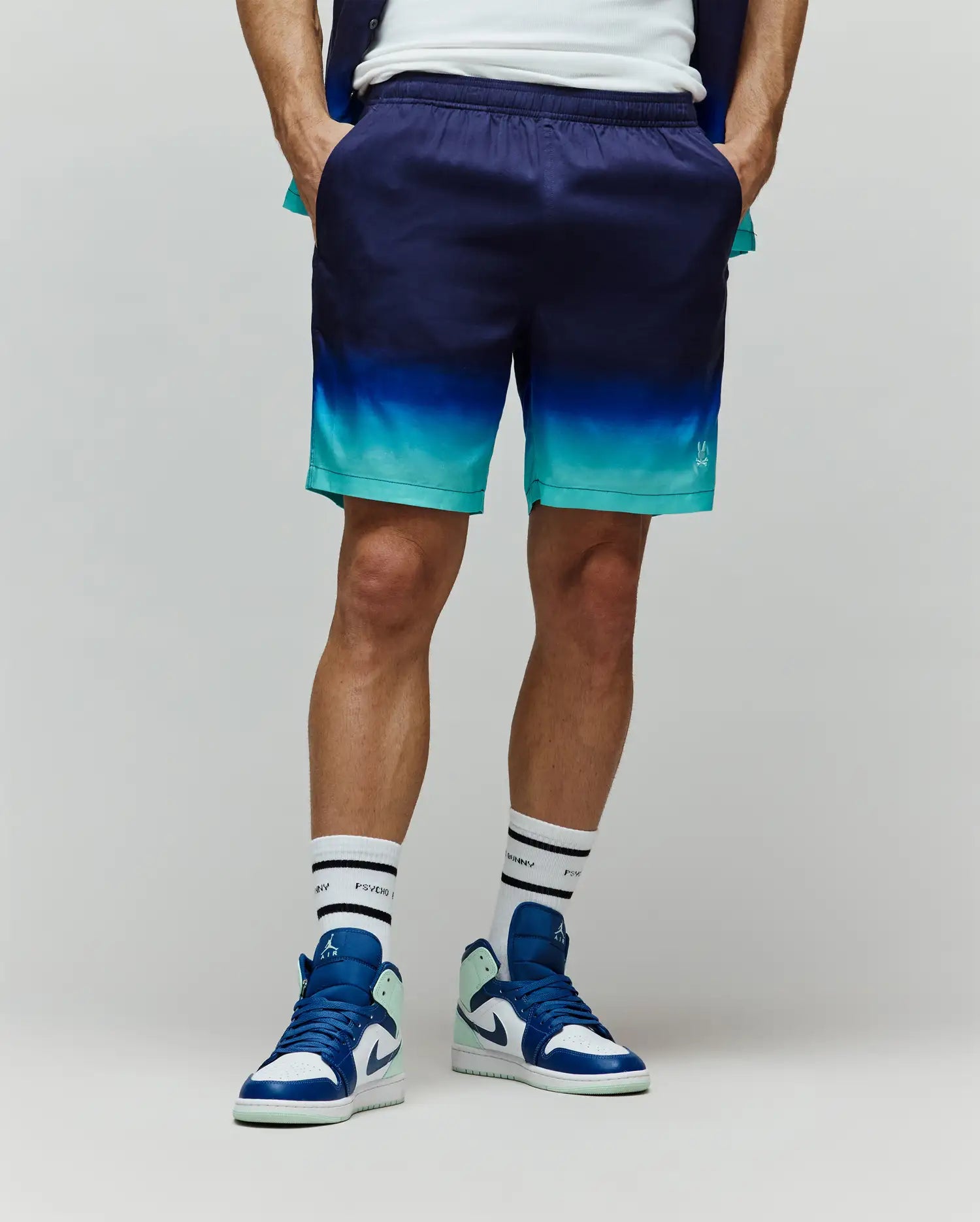 Mens Dax Tencel Short, relaxed fit, featuring a smooth fabric with a dark navy to bright teal gradient, and a small white Psycho Bunny skull logo on the lower right leg.