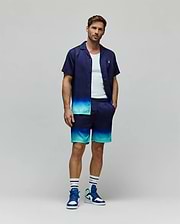 Relaxed fit navy short-sleeve button-up shirt and Mens Dax Tencel Short, with a vibrant blue and teal ombre fade. Shirt has a small embroidered Psycho Bunny skull logo, shorts include Psycho Bunny branding.