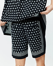 Mens Nick Tencel Short 7, black with an all-over white Psycho Bunny skull logo diamond pattern, featuring white triple stripe trim on the side seams and hem, in a relaxed Tencel fabric.