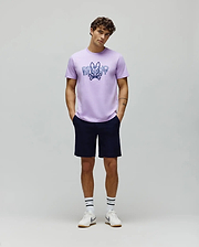Lavender jersey t-shirt with a large distressed blue Psycho Bunny skull logo and text graphic on the chest, paired with classic fit navy MENS SHIRO TWILL SHORT.