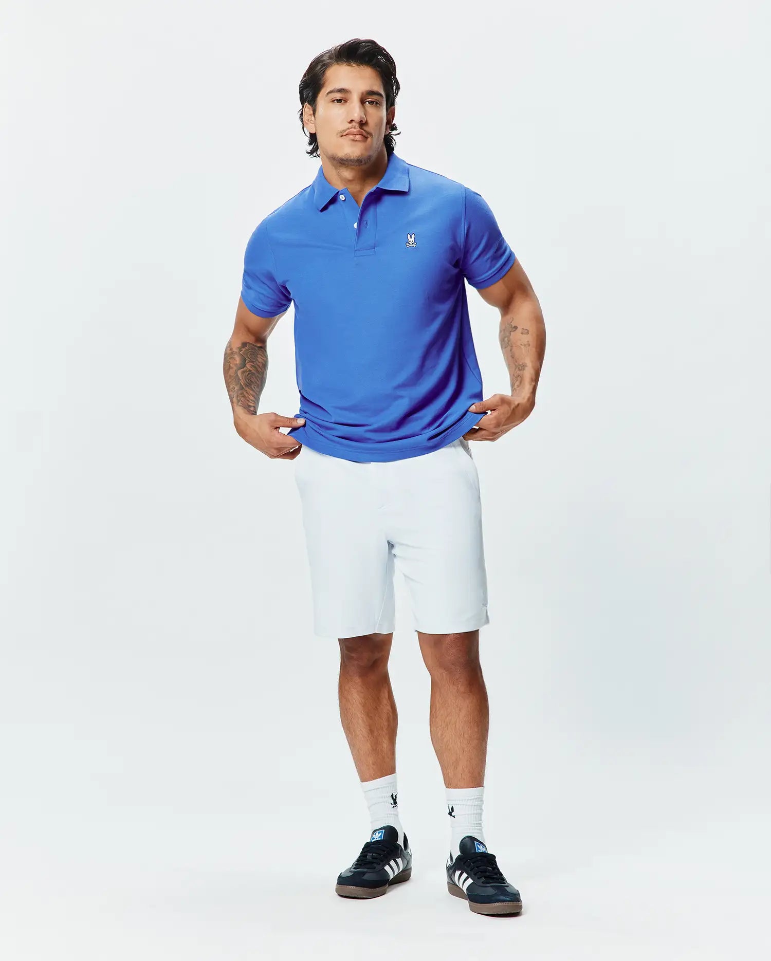 Royal blue pique polo shirt with a classic fit, red collar accent, and small white embroidered Psycho Bunny skull logo on the left chest, paired with white Mens Shiro Twill Short.