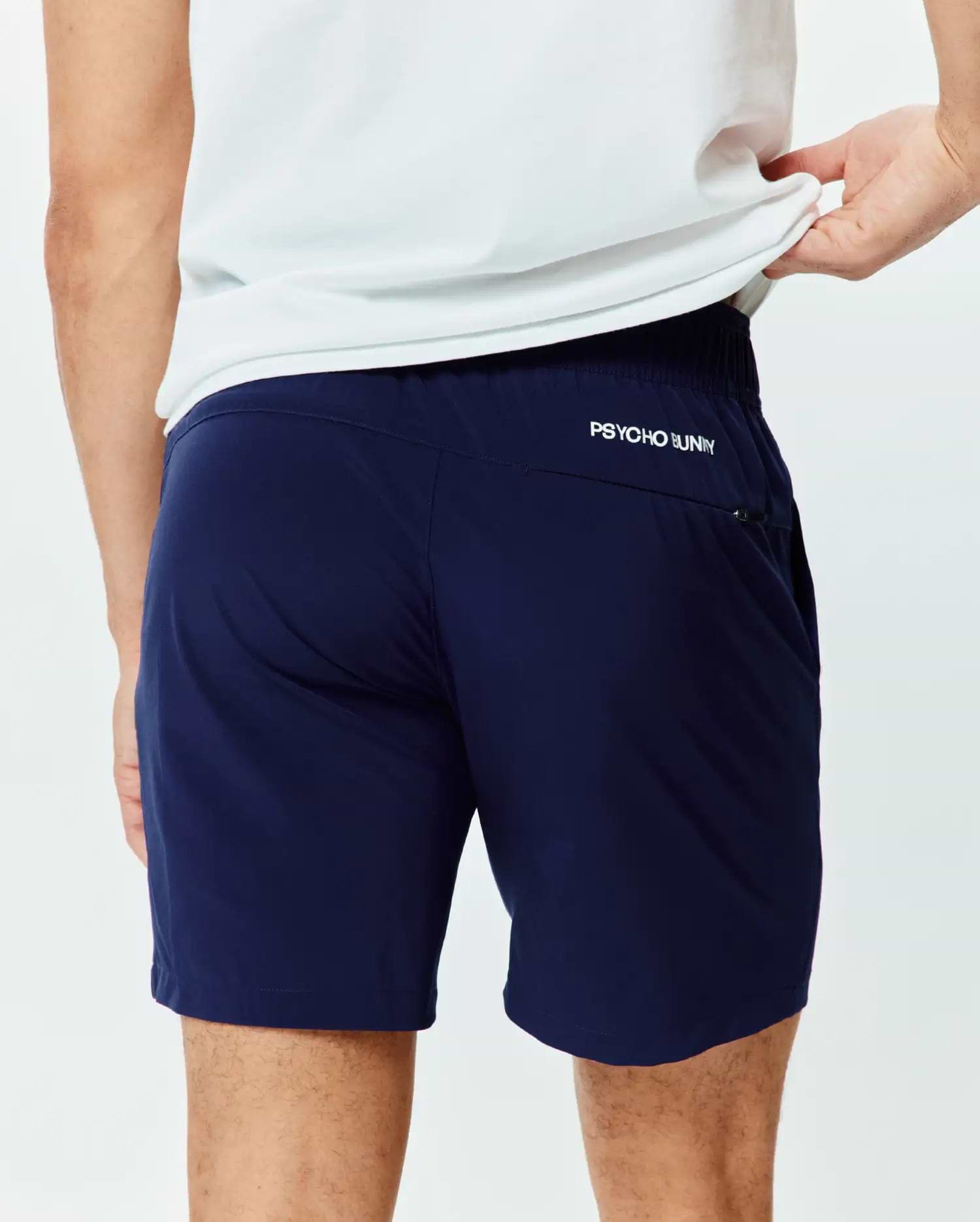Mens Blaze Sport Short in navy, featuring a smooth performance fabric and a classic fit. A small white PSYCHO BUNNY text logo is on the upper back, with a zippered side pocket.