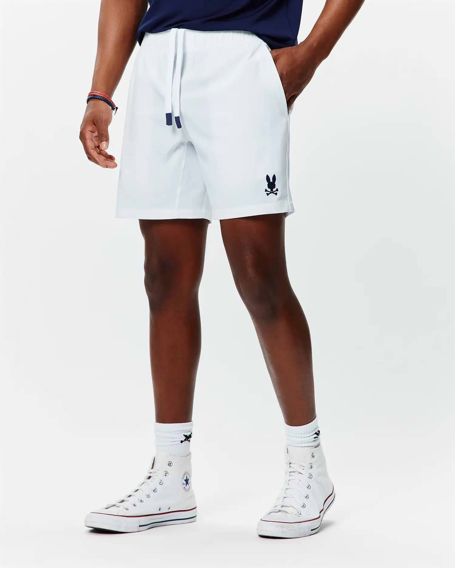 Mens Blaze Sport Short, white, relaxed fit, smooth performance fabric, featuring navy drawstring tips and a small embroidered navy Psycho Bunny skull logo on the lower left leg.