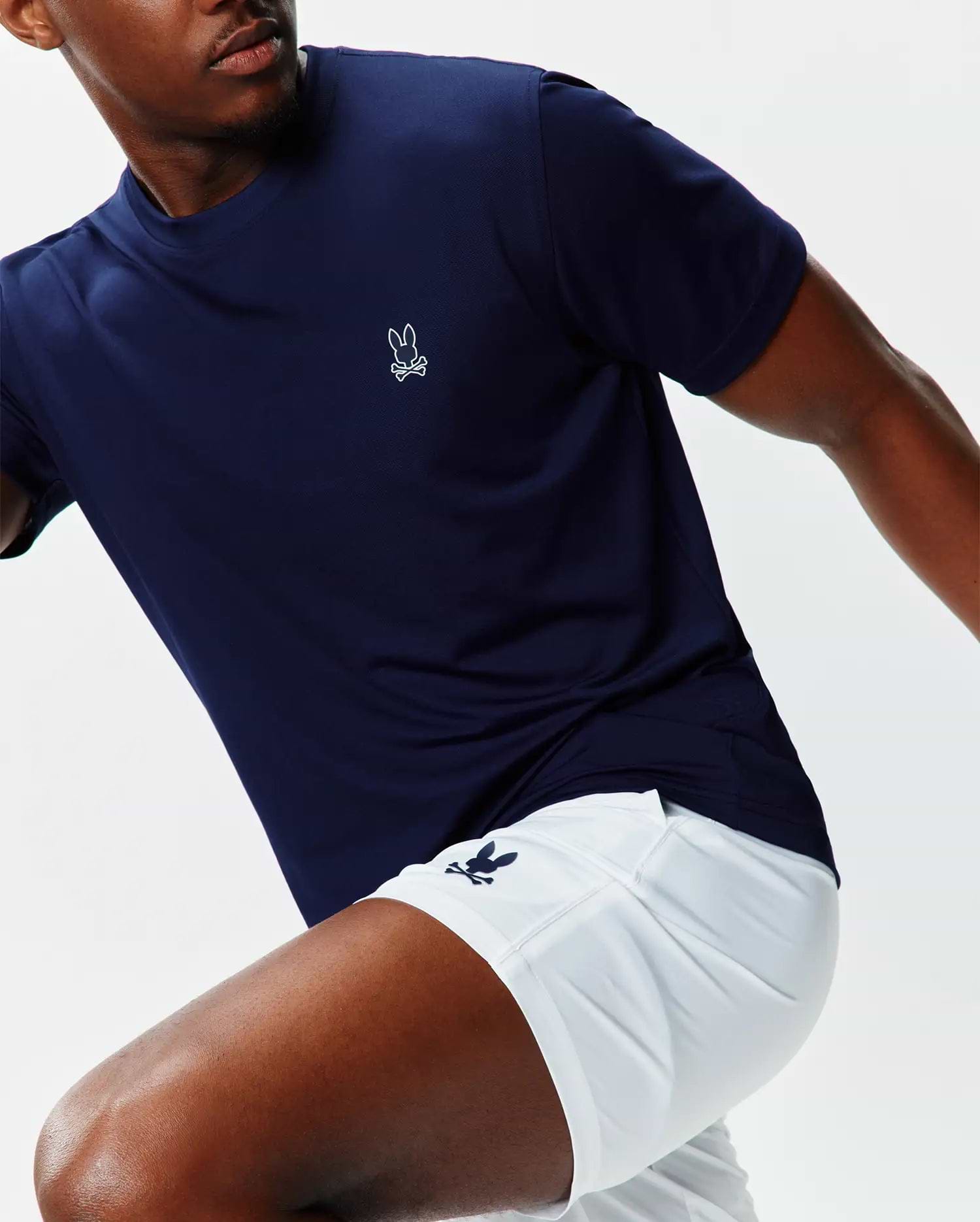 Navy performance jersey t-shirt with a small white embroidered Psycho Bunny skull logo on the left chest, paired with white Mens Blaze Sport Short featuring a navy bunny skull logo on the left leg.