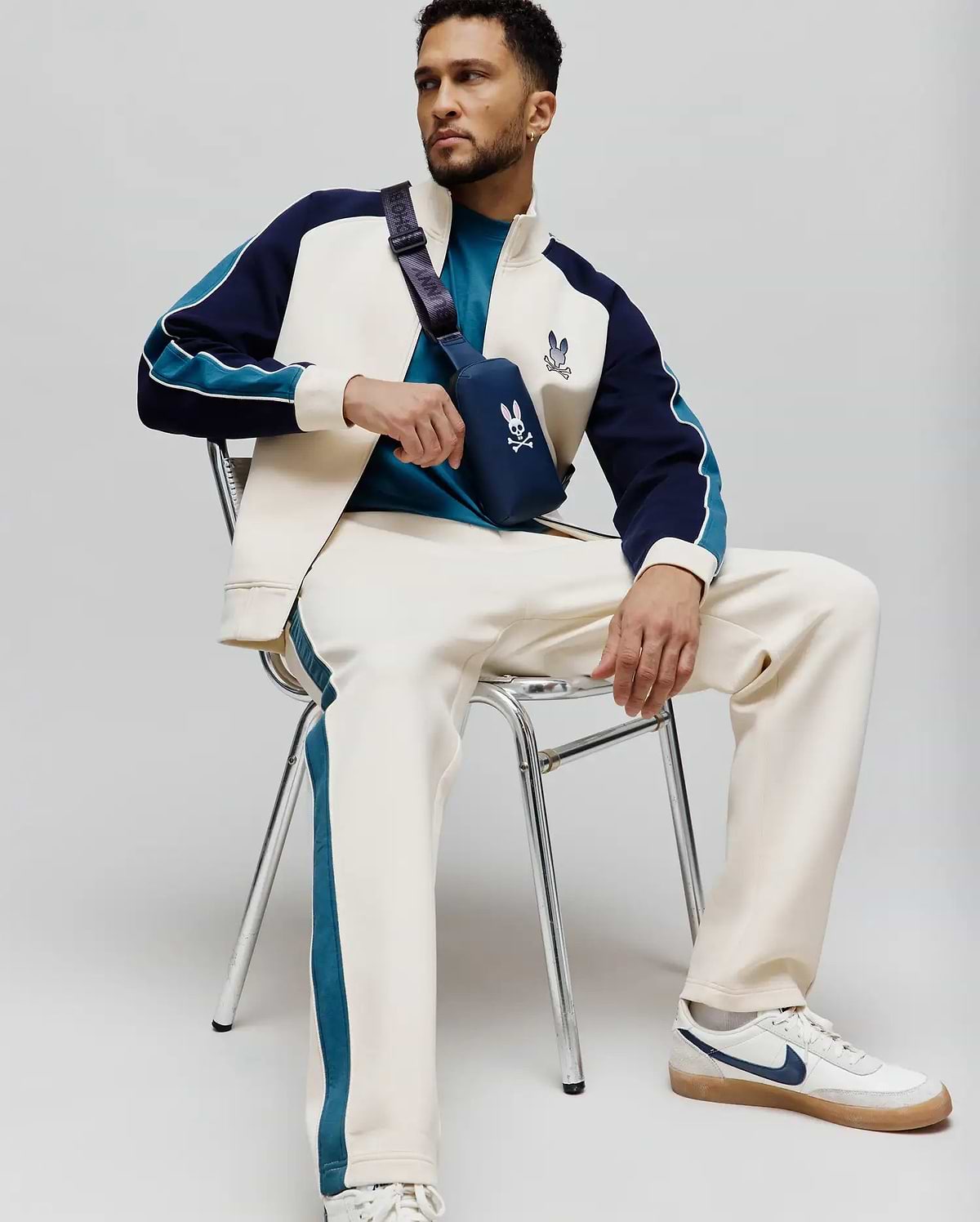 Cream MENS CASPIAN TRACK PANT with teal side stripes, paired with a cream, navy, and teal color-block track jacket featuring an embroidered Psycho Bunny logo, and a teal t-shirt. (4)