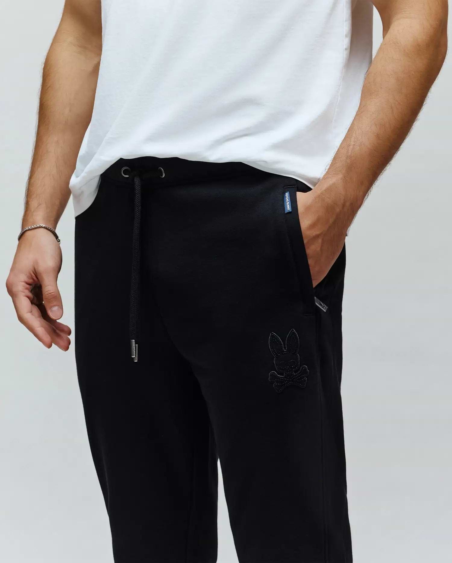 Black Mens Barry Joggers, relaxed fit, smooth jersey fabric, featuring a drawstring waist with silver tips, and a large tonal embroidered Psycho Bunny skull logo on the left thigh.