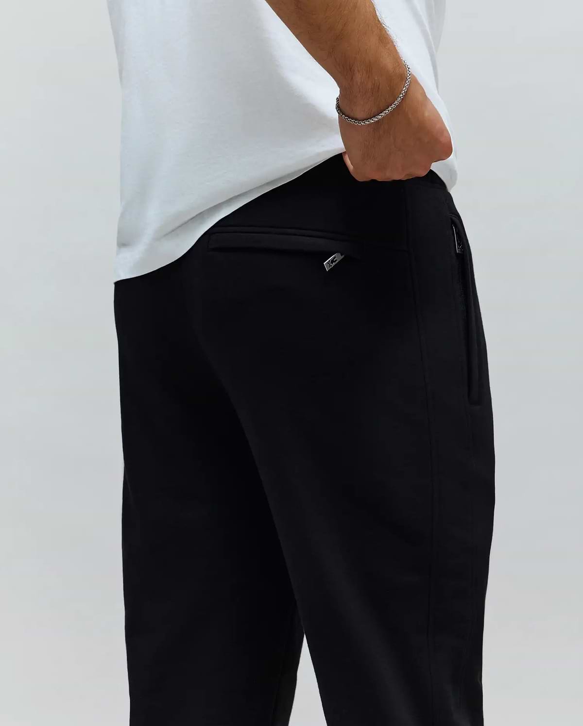 Mens Barry Joggers, black, relaxed fit, crafted from smooth knit fabric. Features a rear welt pocket and a side zipper pocket with a small silver Psycho Bunny logo pull.