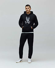 Black classic fit French terry hoodie with a large distressed white Psycho Bunny skull logo on the chest, paired with black slim Mens Barry Joggers featuring a small embroidered bunny logo.