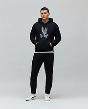 Black classic fit French terry hoodie with a large distressed white Psycho Bunny skull logo on the chest, paired with black slim Mens Barry Joggers featuring a small embroidered bunny logo.