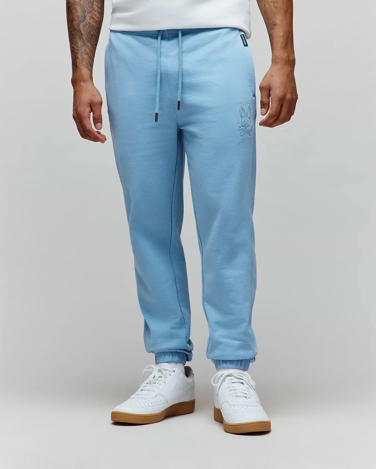 Mens Barry Joggers in light blue, featuring a relaxed fit and soft french terry fabric. Tonal embroidered Psycho Bunny skull logo on the left thigh, drawstring waist with black tips, and ribbed cuffs. (1)