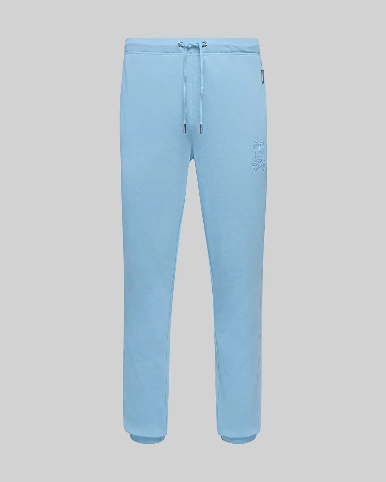 Mens Barry Joggers in light blue, featuring a relaxed fit, soft jersey fabric, drawstring waist, ribbed cuffs, and a small embroidered Psycho Bunny skull logo on the left thigh. (5)