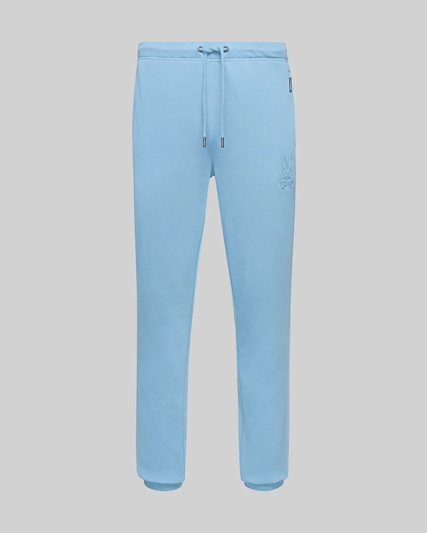 Mens Barry Joggers in light blue, featuring a relaxed fit, soft jersey fabric, drawstring waist, ribbed cuffs, and a small embroidered Psycho Bunny skull logo on the left thigh. (5)