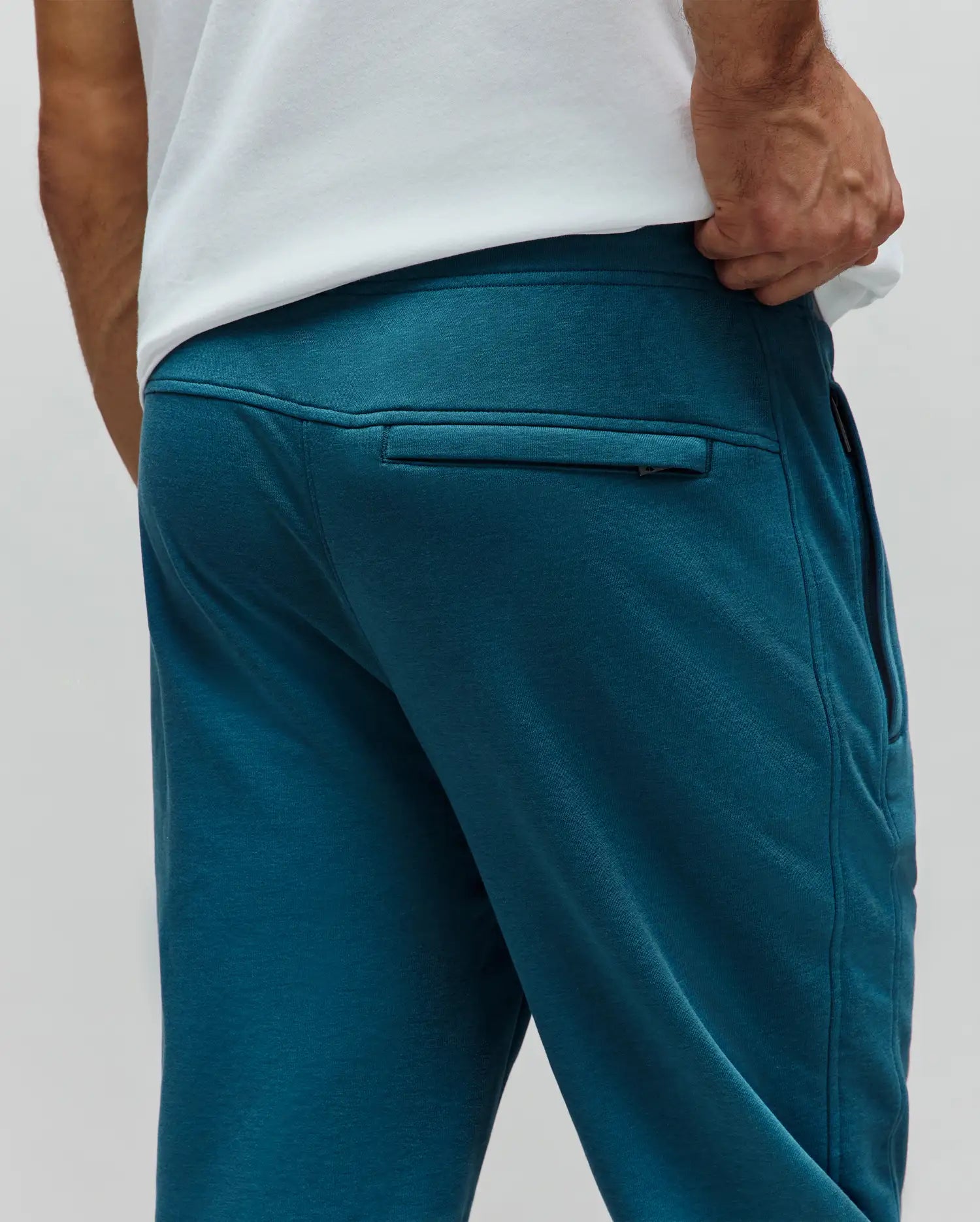 Mens Barry Joggers in deep teal French terry, featuring a relaxed fit, elastic waistband, and a horizontal zippered back pocket with subtle stitching details.