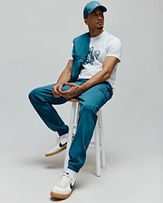Teal baseball cap with white Psycho Bunny skull logo, white classic fit jersey t-shirt with large distressed green/blue Psycho Bunny graphic, and relaxed fit teal french terry Mens Barry Joggers featuring a small embroidered skull logo.