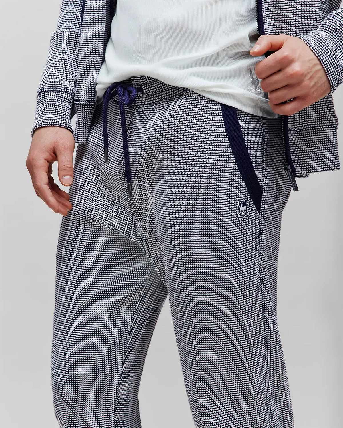 Mens Maxton Two Tone Jogger in a navy and white micro-patterned knit, featuring a classic fit, navy side stripe, drawstrings, and a small embroidered Psycho Bunny skull logo on the left thigh.