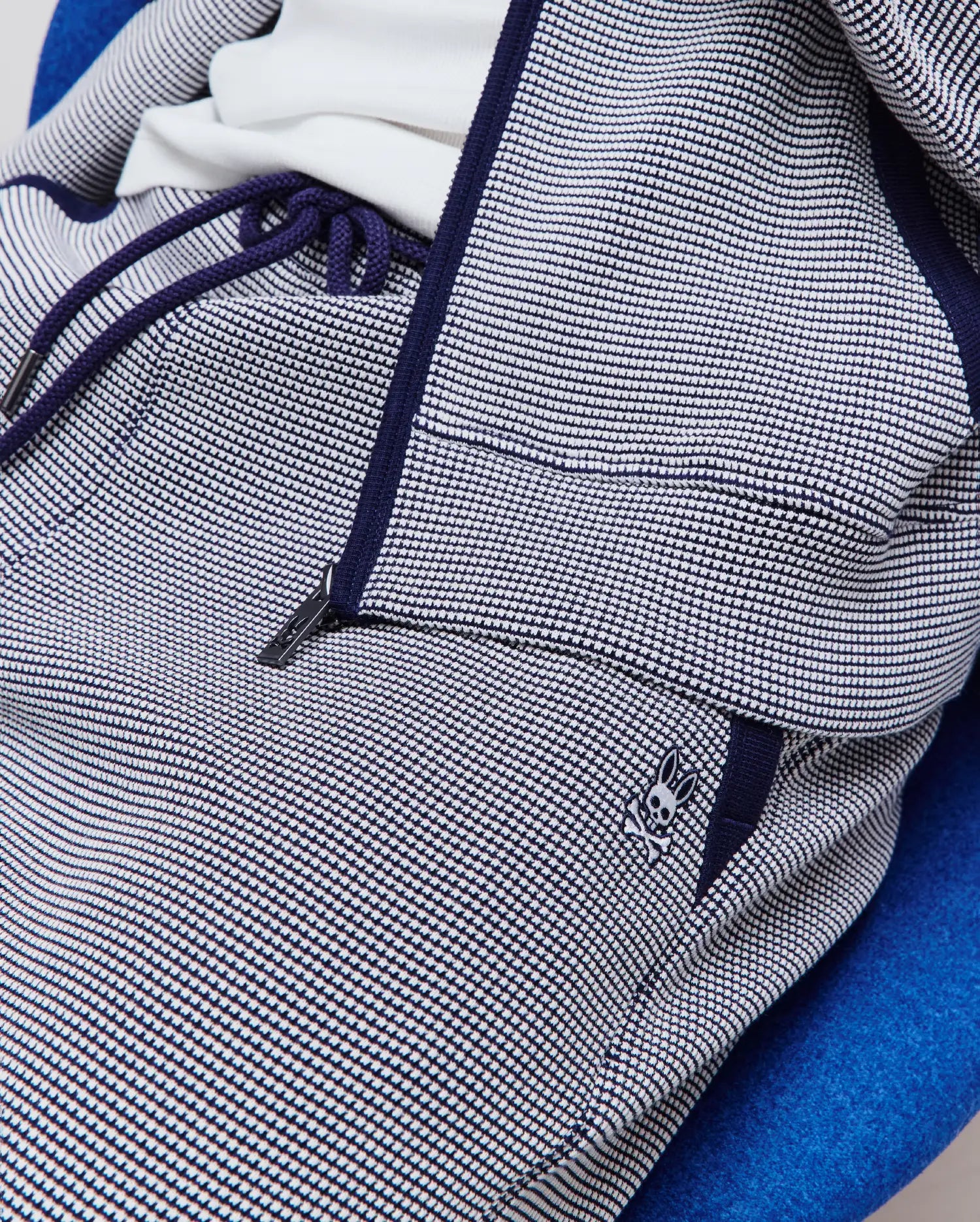 Mens Maxton Two Tone Jogger in navy blue and white two-tone textured knit, featuring a relaxed fit, navy drawstrings, zippered pocket, and small embroidered Psycho Bunny skull logo on the left hip.
