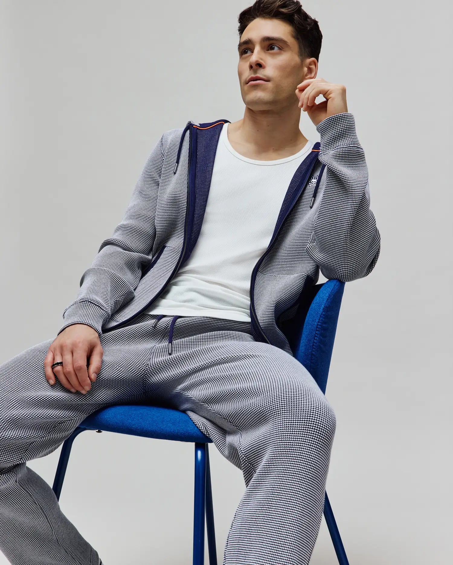 Mens Maxton Two Tone Jogger and matching full-zip hoodie in a white and navy micro-textured knit, featuring a small embroidered Psycho Bunny skull logo on the chest, navy drawstrings, and orange accent trim, offering a relaxed fit.