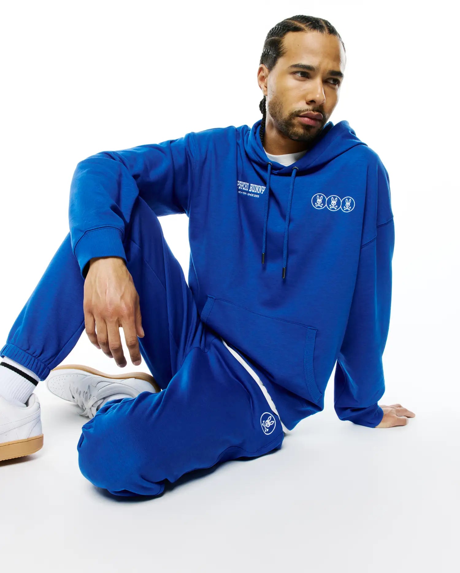 Royal blue relaxed fit French terry hoodie with white Psycho Bunny text and triple bunny skull chest logos, paired with matching Mens Nathaniel Sweatpant featuring a white side stripe and left thigh bunny skull logo. (4)