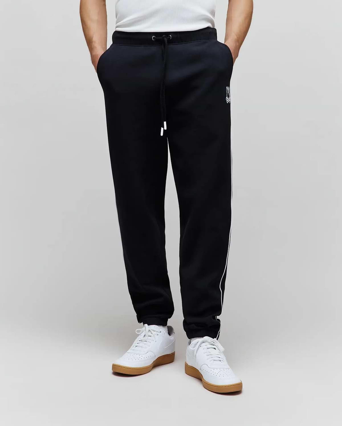 Mens Toby Track Pants in black French terry, featuring a relaxed fit, white drawstring, white Psycho Bunny skull logo on the left thigh, and white side stripes.